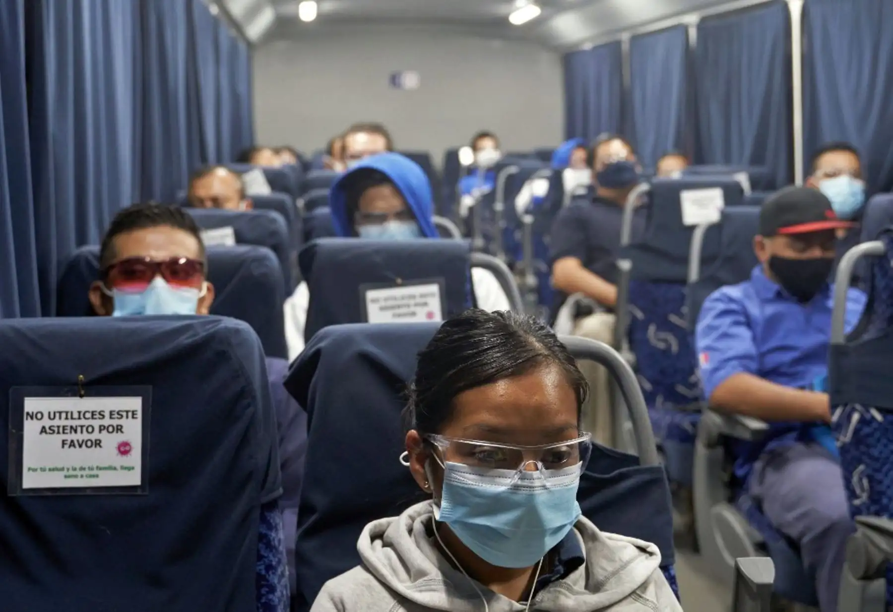 Los empleados de una fábrica de partes de camiones son transportados a trabajar en un autobús manteniendo distancias de seguridad mientras se preparan para reanudar las actividades. Foto: AFP