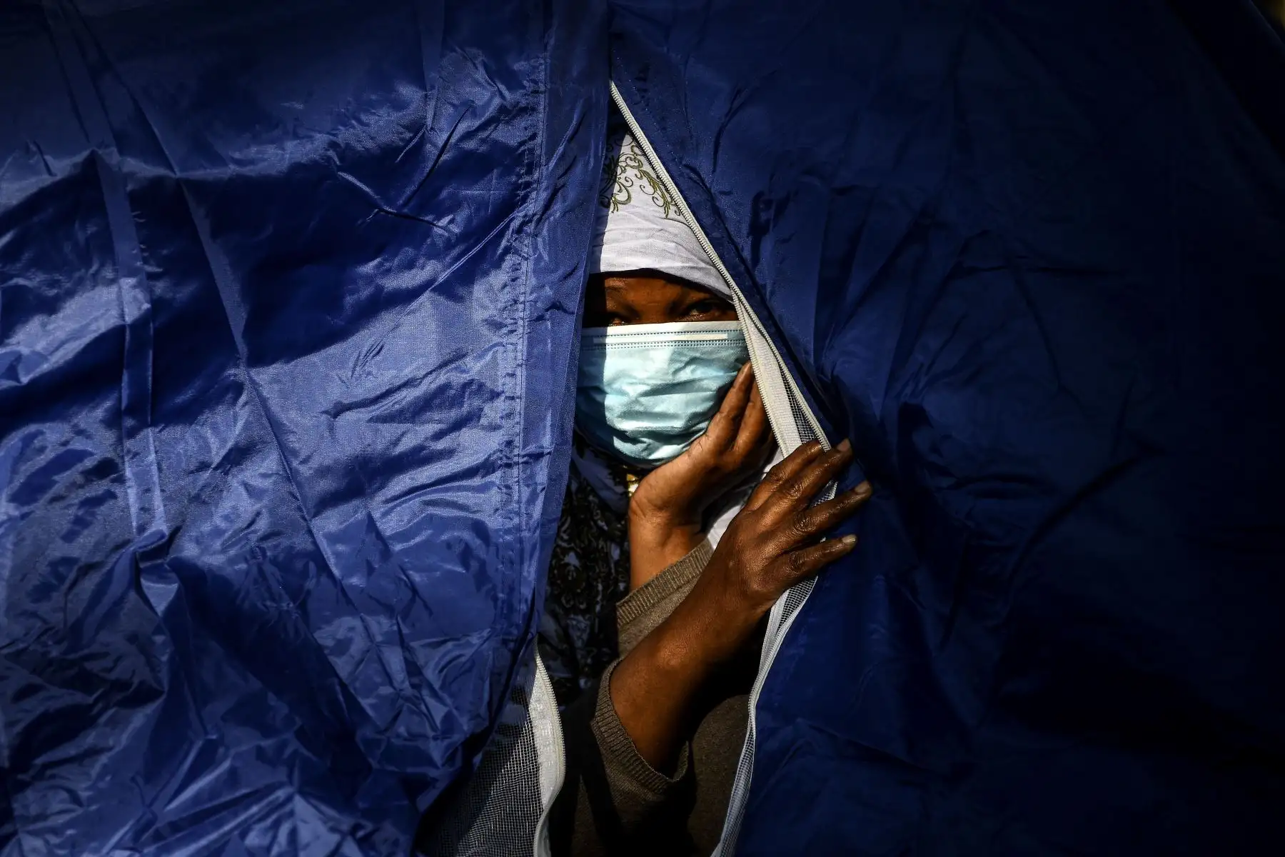 Una mujer somalí se asoma desde su tienda de campaña en un campamento improvisado establecido durante la noche por voluntarios de la organización benéfica Utopia 56 y que alberga a más de 50 migrantes, incluidos refugiados y solicitantes de asilo, a lo largo del Bassin de la Villette en París. Foto: AFP