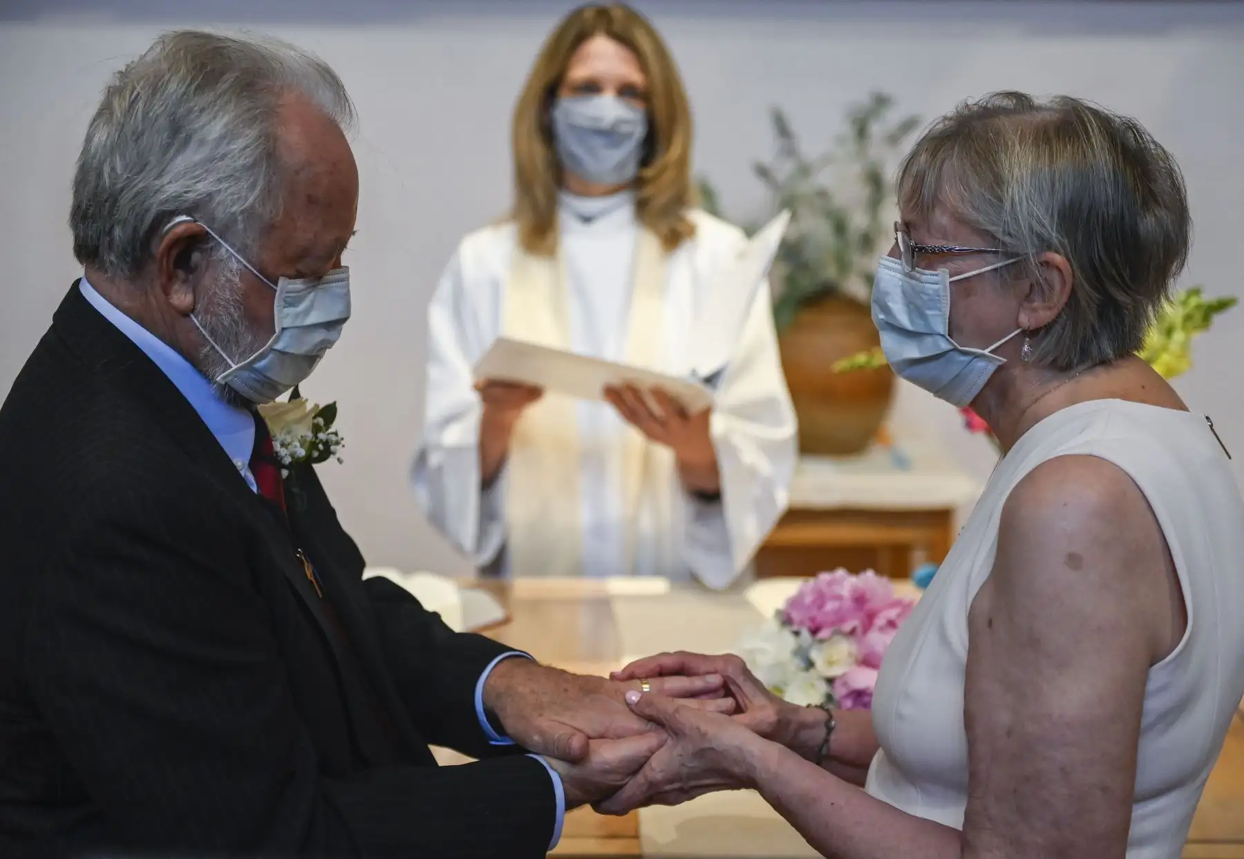 Linda Delk pone un anillo en el dedo de Ardell Hoveskeland mientras la pastora Sarah Scherschligt observa durante su boda socialmente distanciada, mientras familiares y amigos se unen por ZOOM, en la Iglesia Luterana de la Paz en Alexandria, Virginia, USA. Foto: AFP