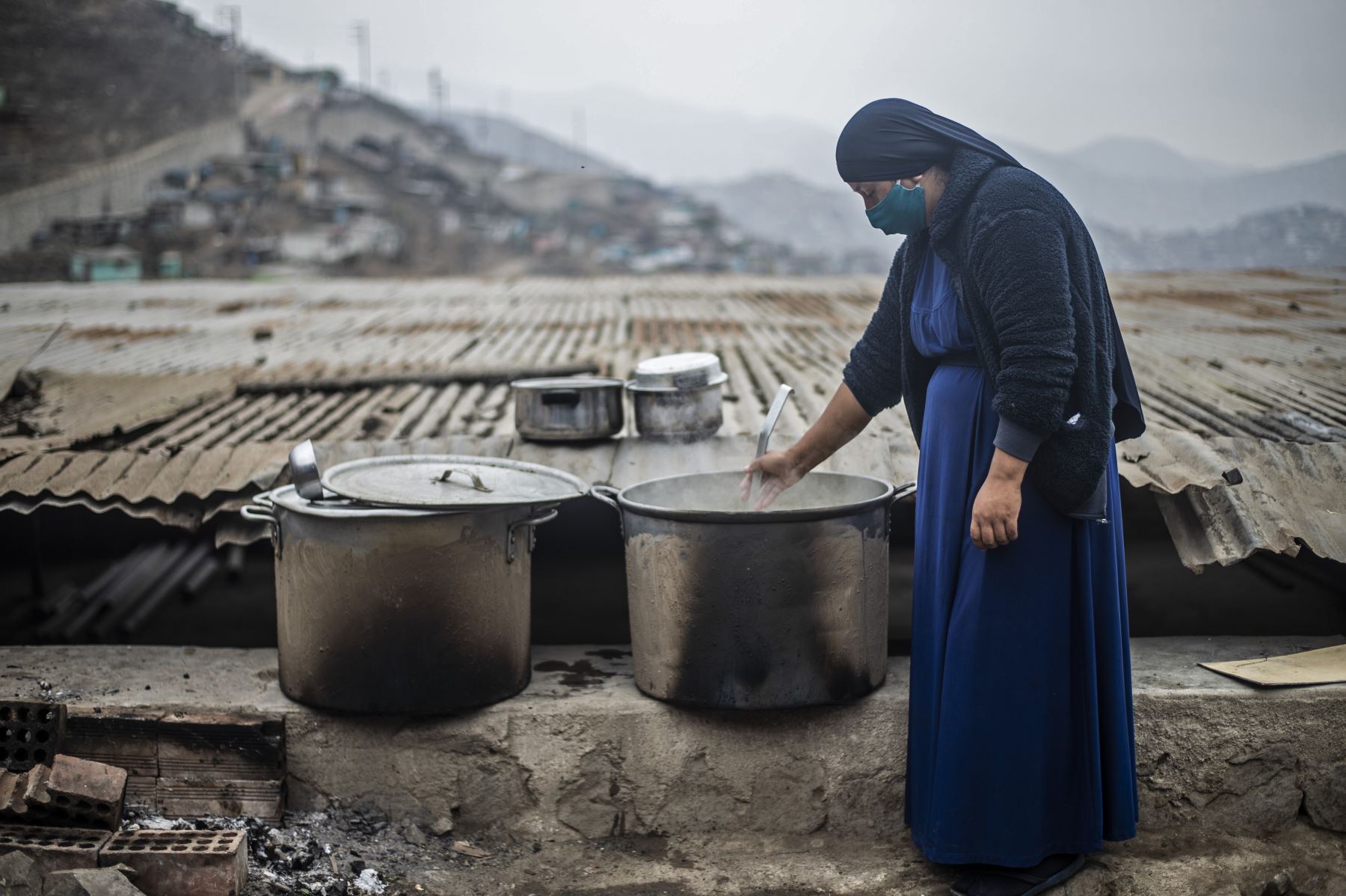Una mujer religiosa evangélica mueve una olla en un comedor comunitario de la sección de Pamplona Alta, que también sufre escasez de agua, en las afueras del sur de Lima. Foto: AFP