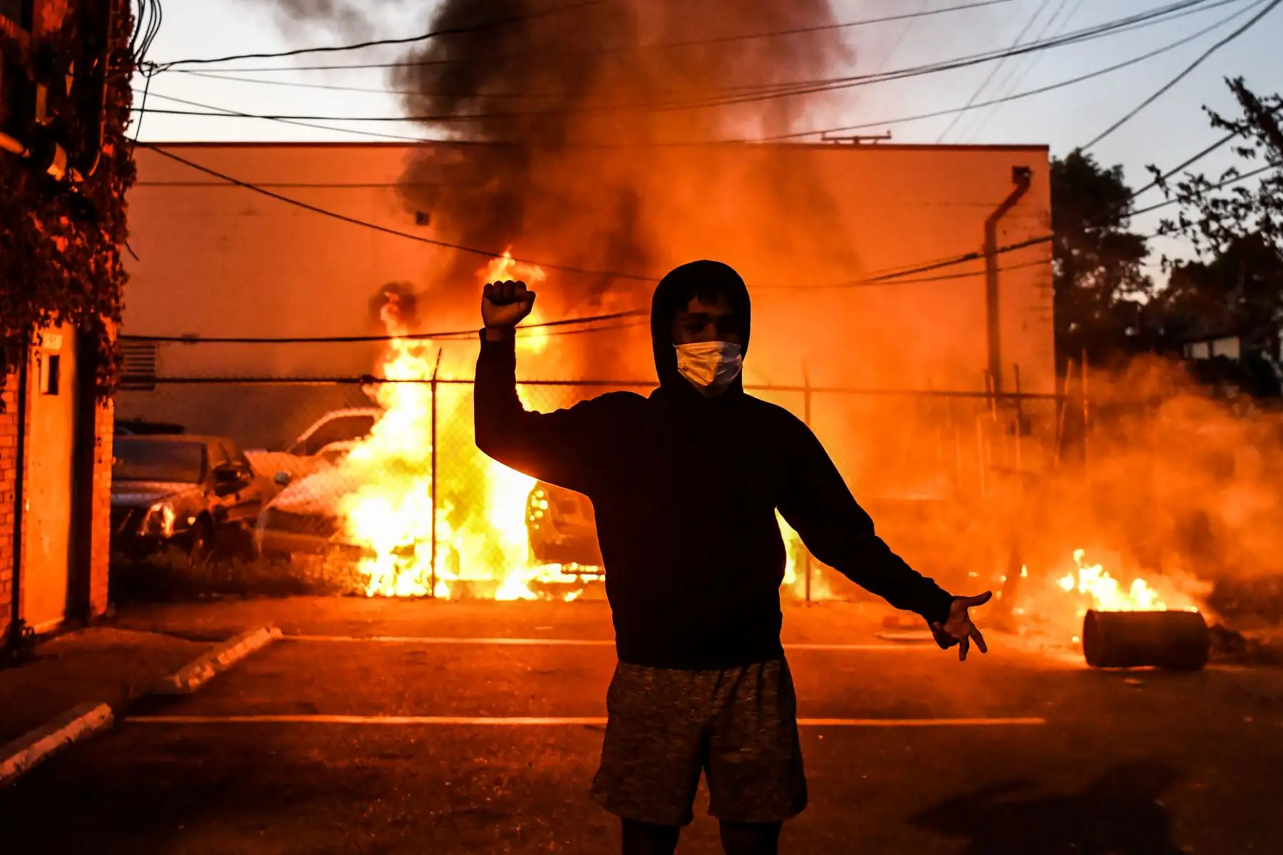 Un manifestante hace un gesto mientras los autos arden detrás de él durante una manifestación en Minneapolis, Minnesota, por la muerte de George Floyd, un hombre negro que murió después de que un policía blanco se arrodilló en su cuello durante varios minutos. Foto: AFP
