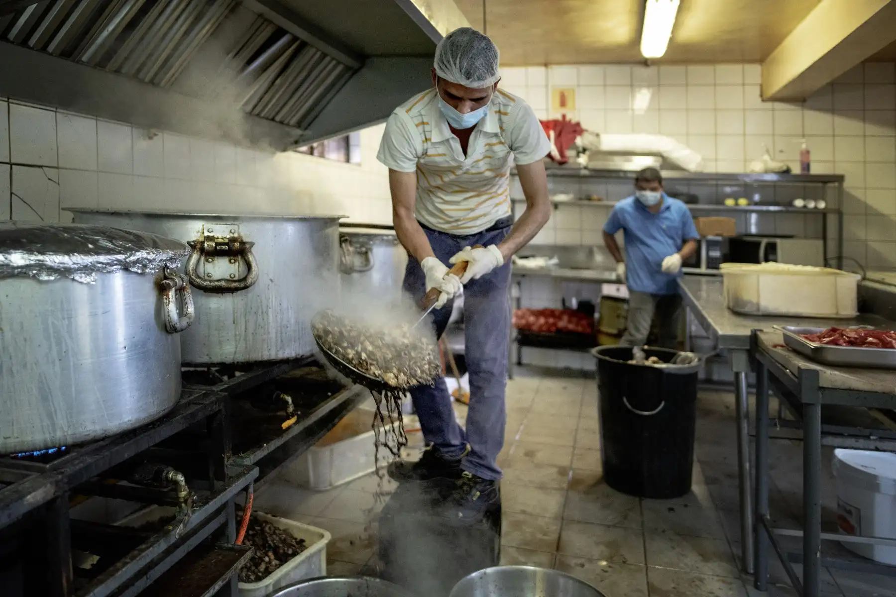 Un trabajador de la cocina prepara comidas calientes en el restaurante indio Thava, en The Gardens, para la distribución diaria de alimentos en un asentamiento informal en Tembisa, Johannesburgo. Foto: AFP