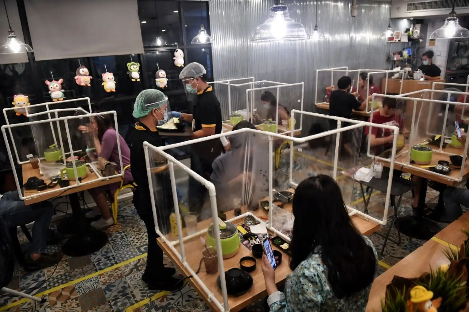 La gente come entre particiones plásticas, configuradas en un esfuerzo por contener cualquier propagación del coronavirus COVID-19, en el restaurante Penguin Eat Shabu en Bangkok. Foto: AFP