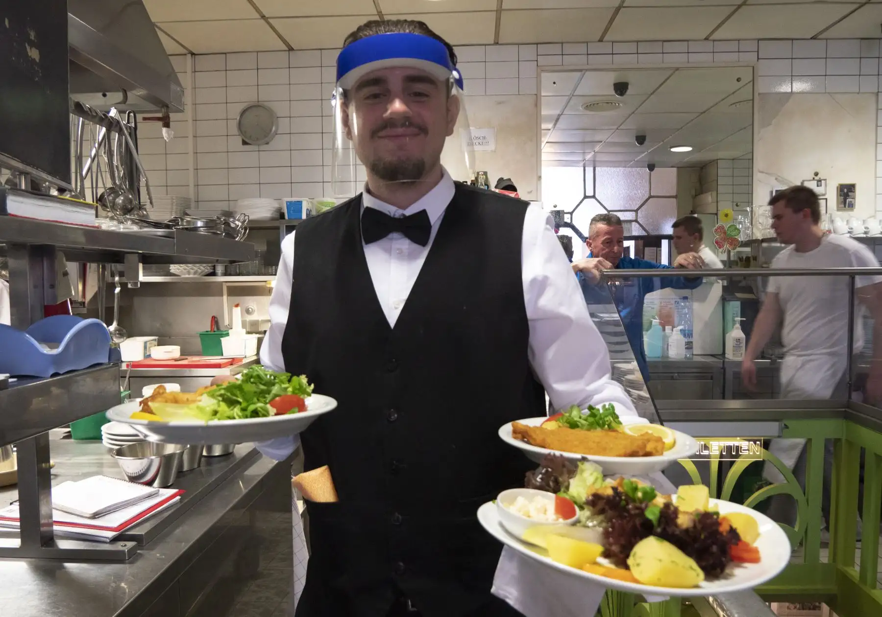 Un camarero usa un protector facial mientras atiende a los clientes en el Café Prueckel en Viena, Austria. Foto: AFP