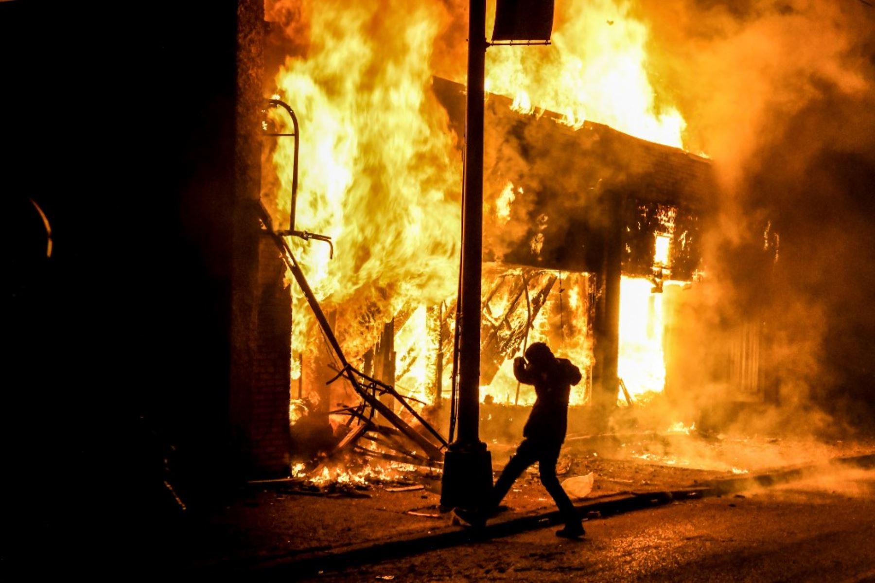 Un manifestante patea una piedra en un edificio en llamas incendiado durante una manifestación en Minneapolis, Minnesota, el 29 de mayo de 2020, en protesta por la muerte de George Floyd. Foto: AFP