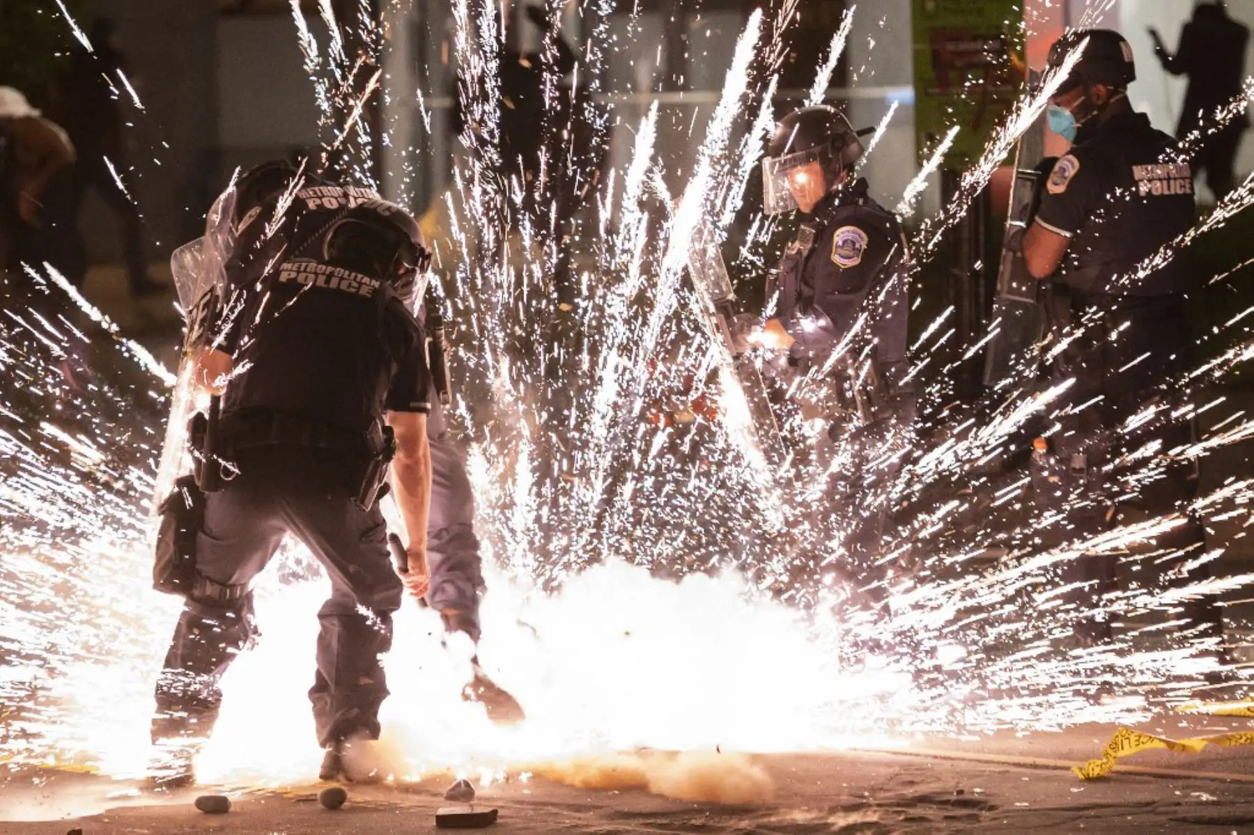 Un petardo arrojado por los manifestantes explota bajo la policía a una cuadra de la Casa Blanca el 30 de mayo de 2020 en Washington DC, durante una protesta por la muerte de George Floyd. Foto: AFP