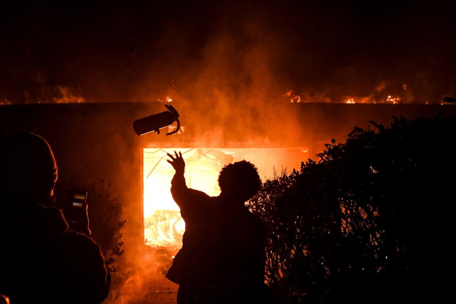 Un manifestante arroja un extintor de incendios en un edificio en llamas durante una manifestación en Minneapolis, Minnesota, el 29 de mayo de 2020, durante protesta por la muerte de George Floyd. Foto: AFP