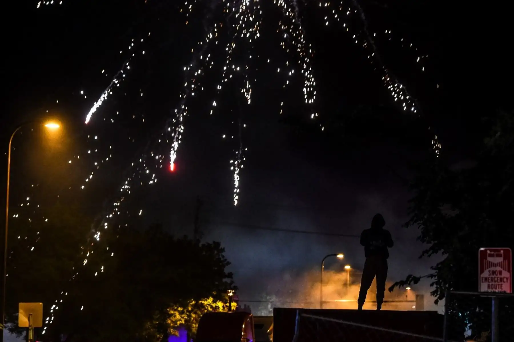 Un manifestante observa a los explotar los petardos en el cielo durante una manifestación en Minneapolis, Minnesota, el 29 de mayo de 2020, durante protesta por la muerte de George Floyd. Foto: AFP