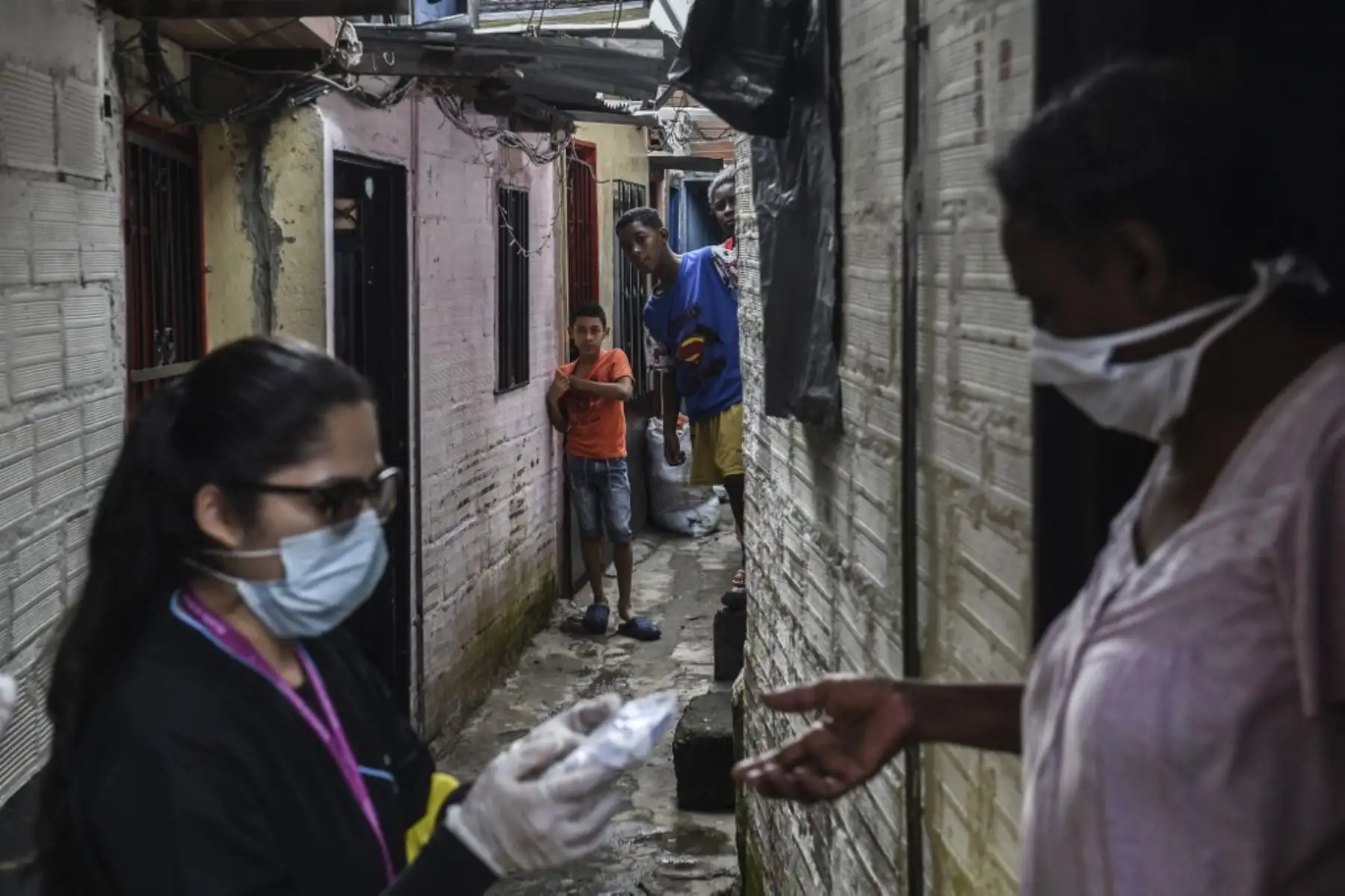 Un trabajador de la salud distribuye máscaras faciales a los locales como medida preventiva contra la propagación del nuevo coronavirus COVID-19, en el barrio de Santa Cruz en Medellín. Foto: AFP