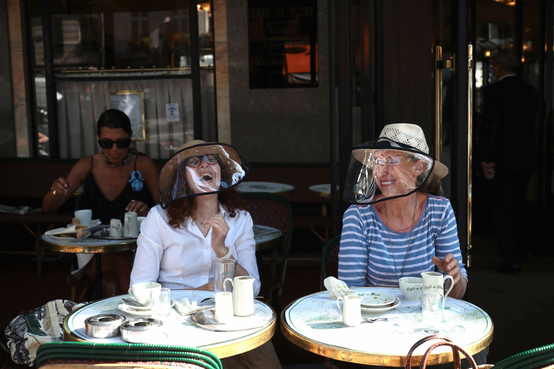 Dos mujeres protegidas con pantallas faciales protectoras ríen en la terraza del mítico "Café de Flore" en París, Francia, este martes.  Foto: EFE