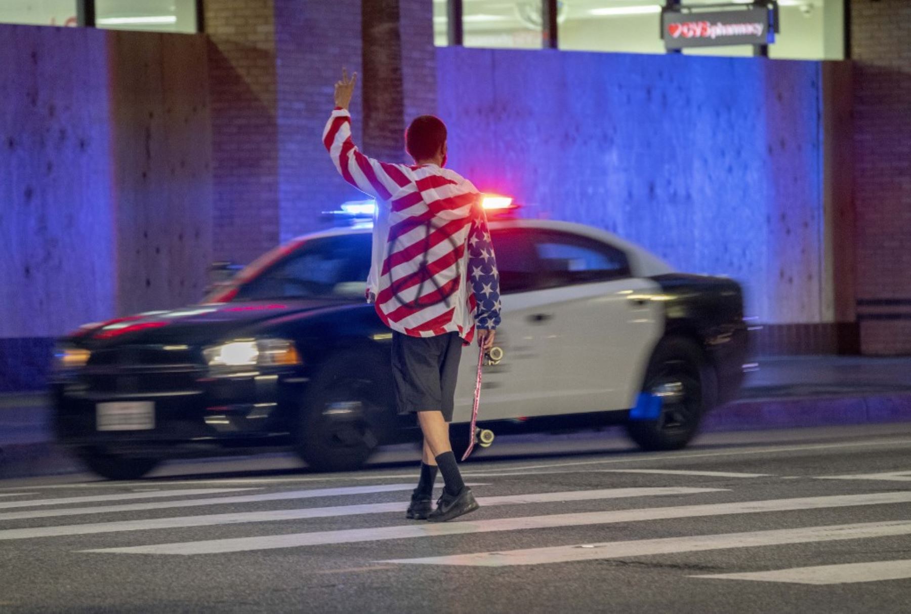 Un manifestante cruza la calle llevando una camisa con signo de paz en Los Ángeles. Foto: AFP