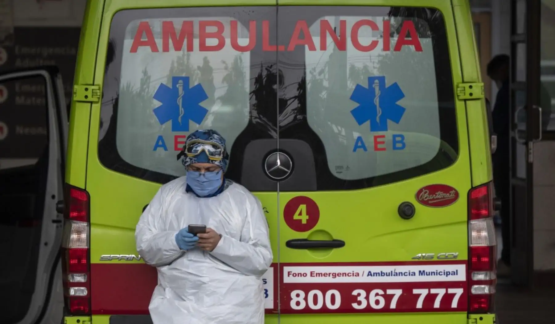 Un trabajador de la salud utiliza su celular junto a una ambulancia que transportaba a un paciente con síntomas del nuevo coronavirus COVID-19, en Santiago de Chile. Foto: AFP