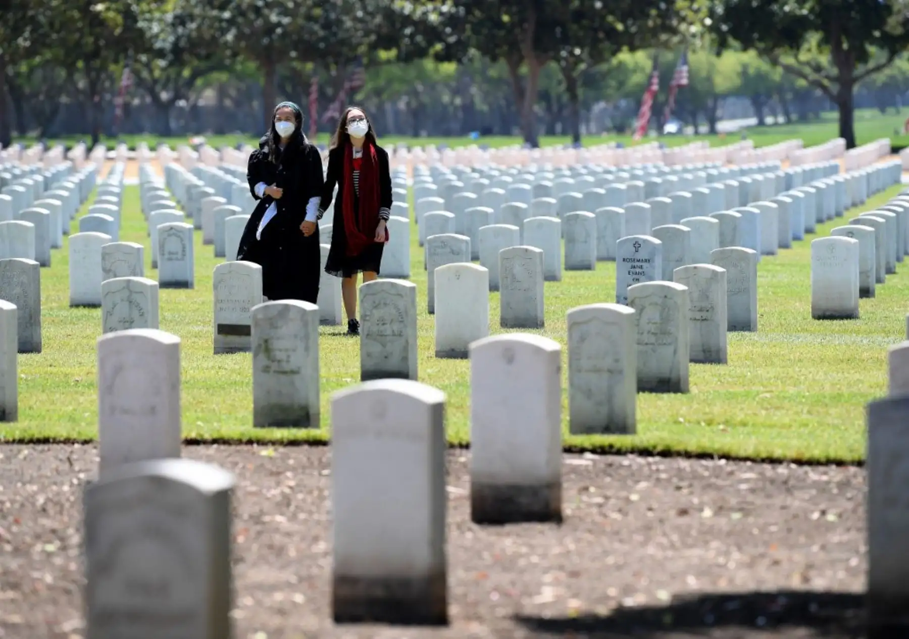 Las personas que usan máscaras protectoras respetan a sus seres queridos en el Día de los Caídos en medio de la pandemia de coronavirus (COVID-19) en el Cementerio Nacional de Los Ángeles. Foto: AFP