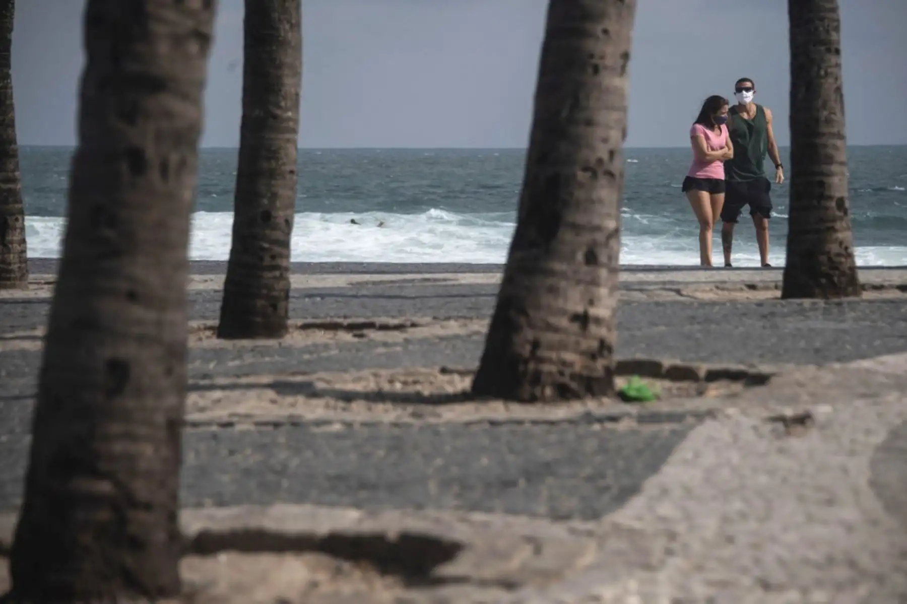 Una pareja con máscara facial caminó en la playa de Arpoador en el estado de Río de Janeiro, Brasil, durante la nueva pandemia de coronavirus COVID-19. Foto: AFP