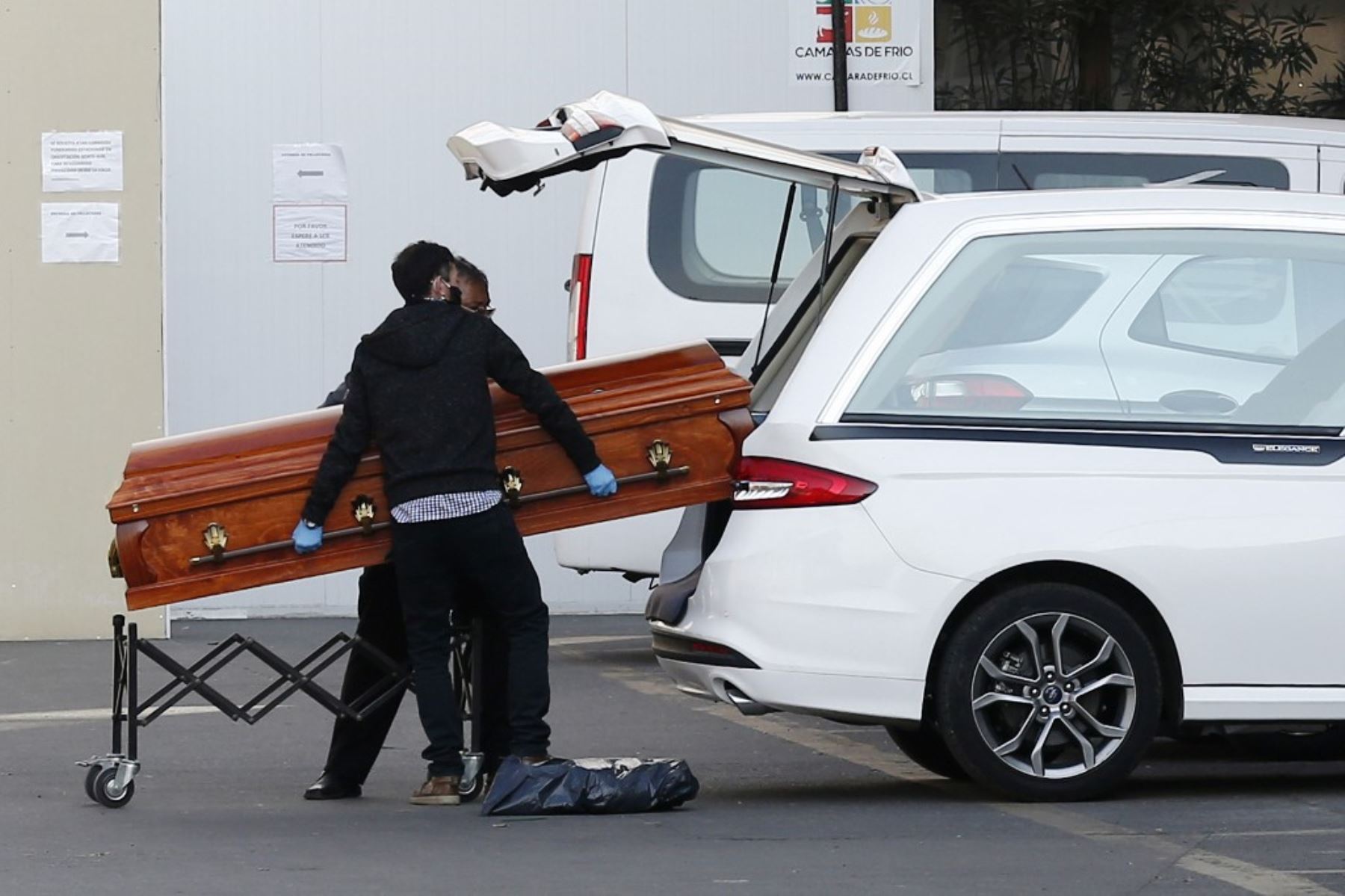 Los empleados de una funeraria pusieron el ataúd que contiene el cuerpo de una persona que murió de COVID-19 dentro de un vehículo, afuera del Hospital San José en Santiago. Foto: AFP