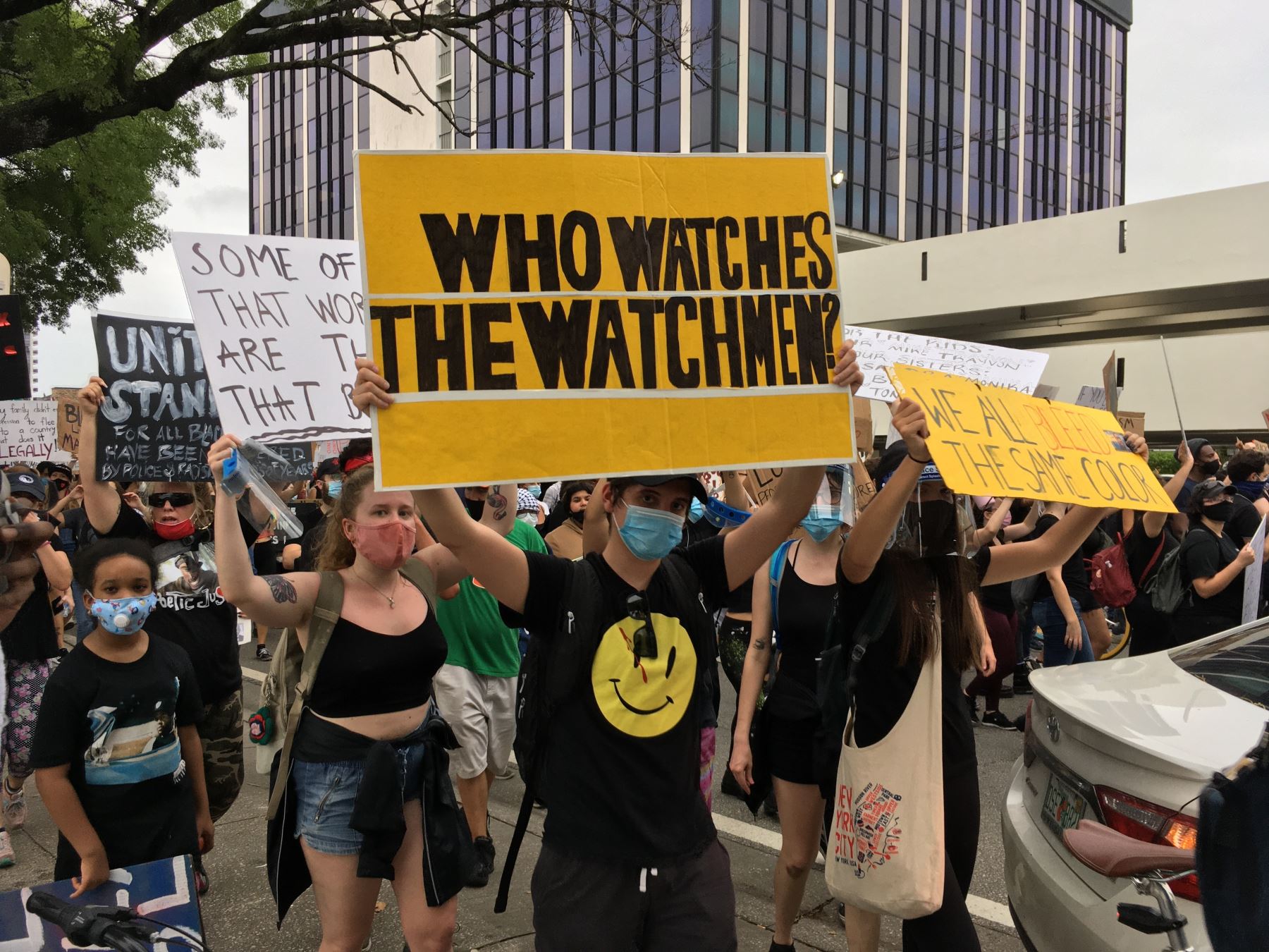 Un hombre con tapabocas sostiene este viernes un cartel con el mensaje "¿Quién vigila a los vigilantes?", durante una manifestación en solidaridad con los afroamericanos George Floyd y Breonna Taylor, en Miami, Florida (EE. UU). Foto: Efe.