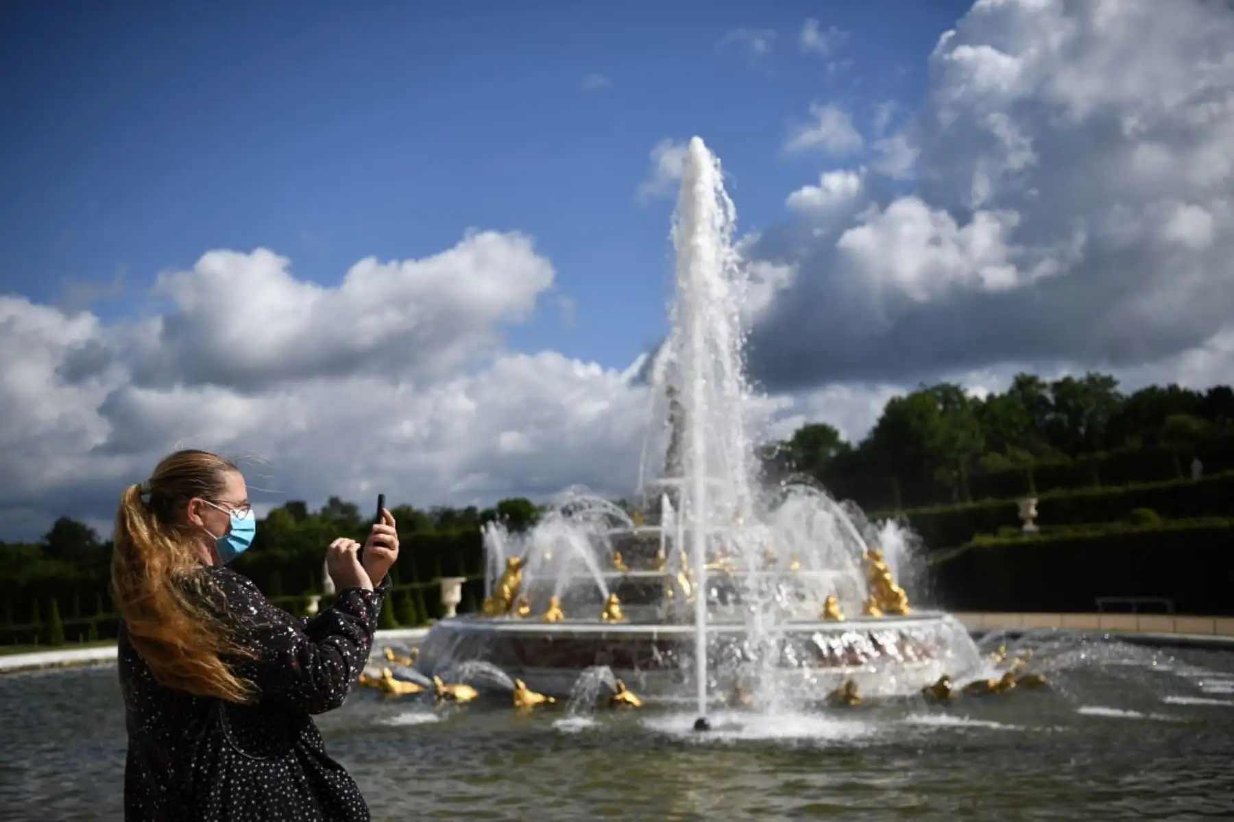 Una mujer usa un teléfono celular mientras visita el parque del histórico castillo francés de Versalles. Foto: AFP