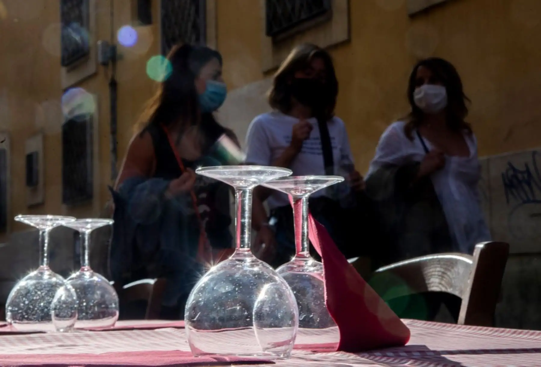 Un grupo de mujeres que llevan máscaras protectoras pasan junto a la terraza de un restaurante en Trastevere, en el centro de Roma. Foto: AFP