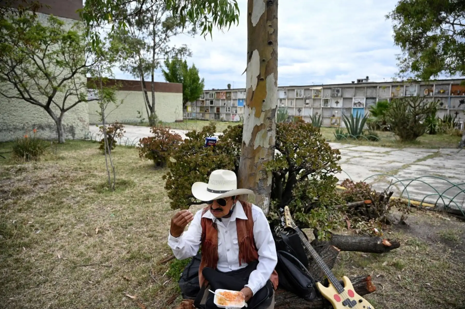Roberto Maldonado, un músico del género musical Norteño, se alimenta antes de ofrecer sus servicios musicales en el Panteón Municipal de Ciudad Nezahualcóyot, en Mexico. Foto: AFP