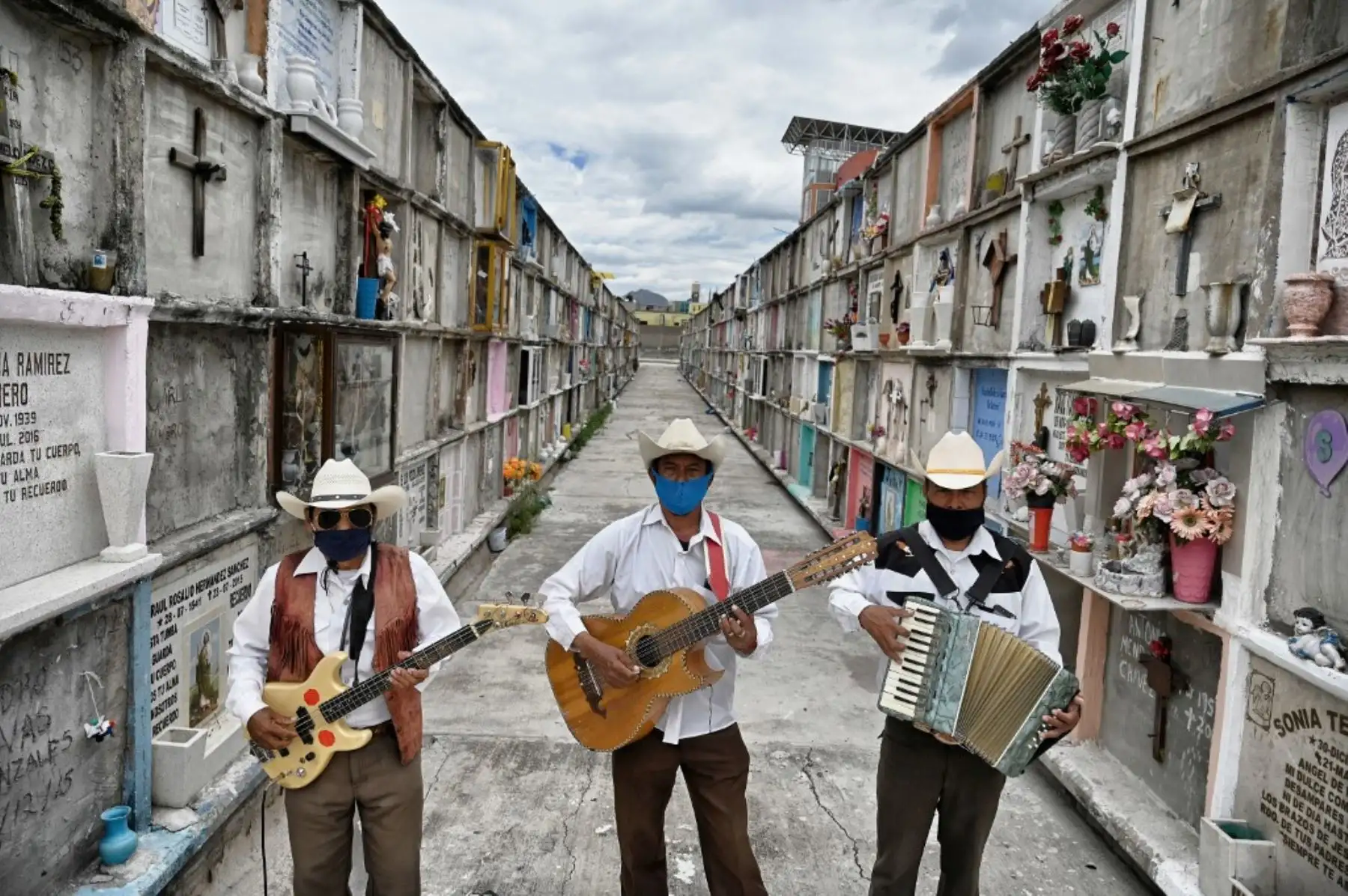 Roberto Maldonado, Humberto Montes e Israel Mundo, músicos del género musical Norteño, posan para una foto mientras esperan un funeral para ofrecer sus servicios artísticos en en el Panteón Municipal de Ciudad, en Mexico. Foto: AFP