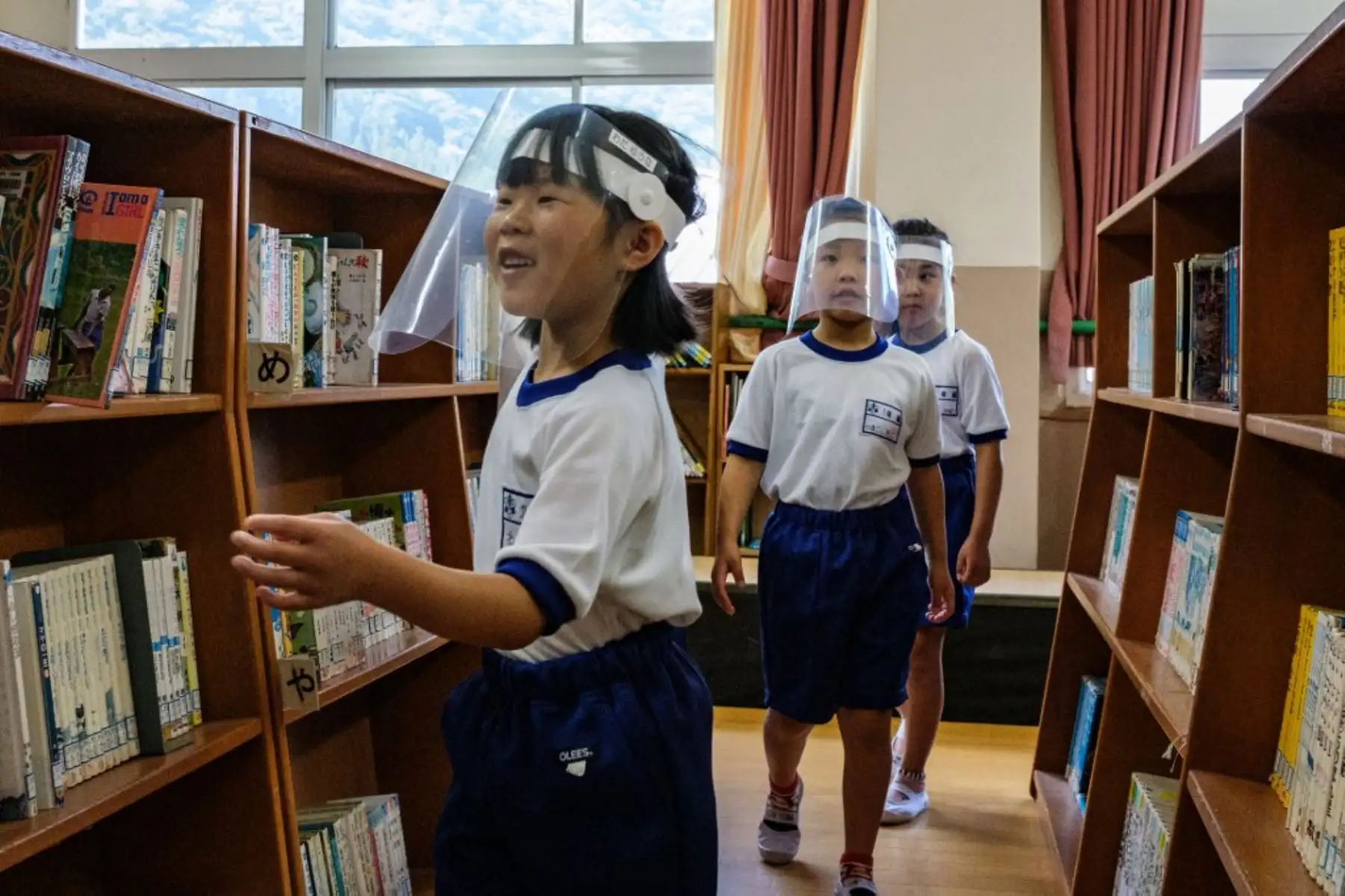 Los estudiantes que usan protectores faciales visitan la biblioteca de la escuela primaria Kinugawa en Nikko, prefectura de Tochigi, Japón. Foto: AFP