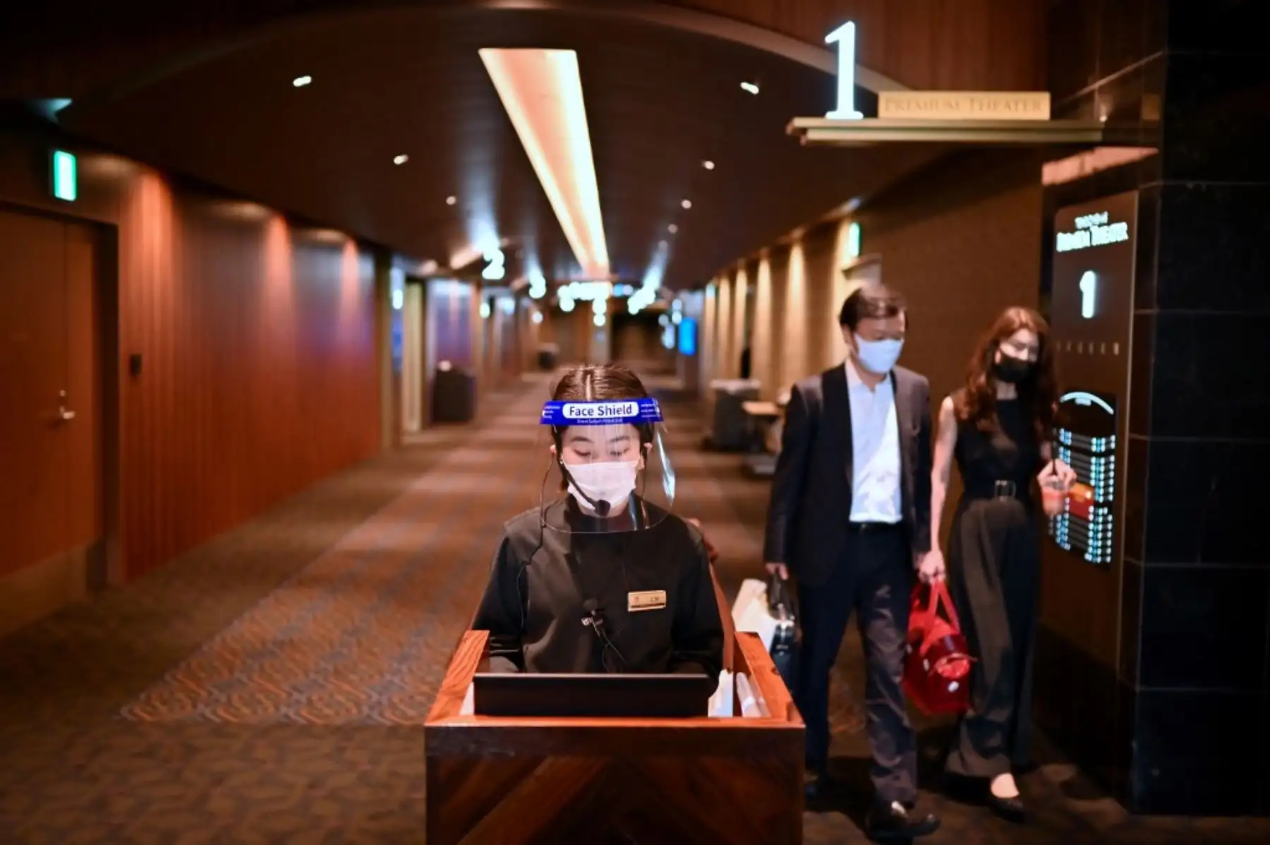 Un empleado usa un protector facial mientras la gente sale de un cine que está reabriendo después de las medidas para frenar la propagación del coronavirus COVID-19, en Tokio. Foto: AFP