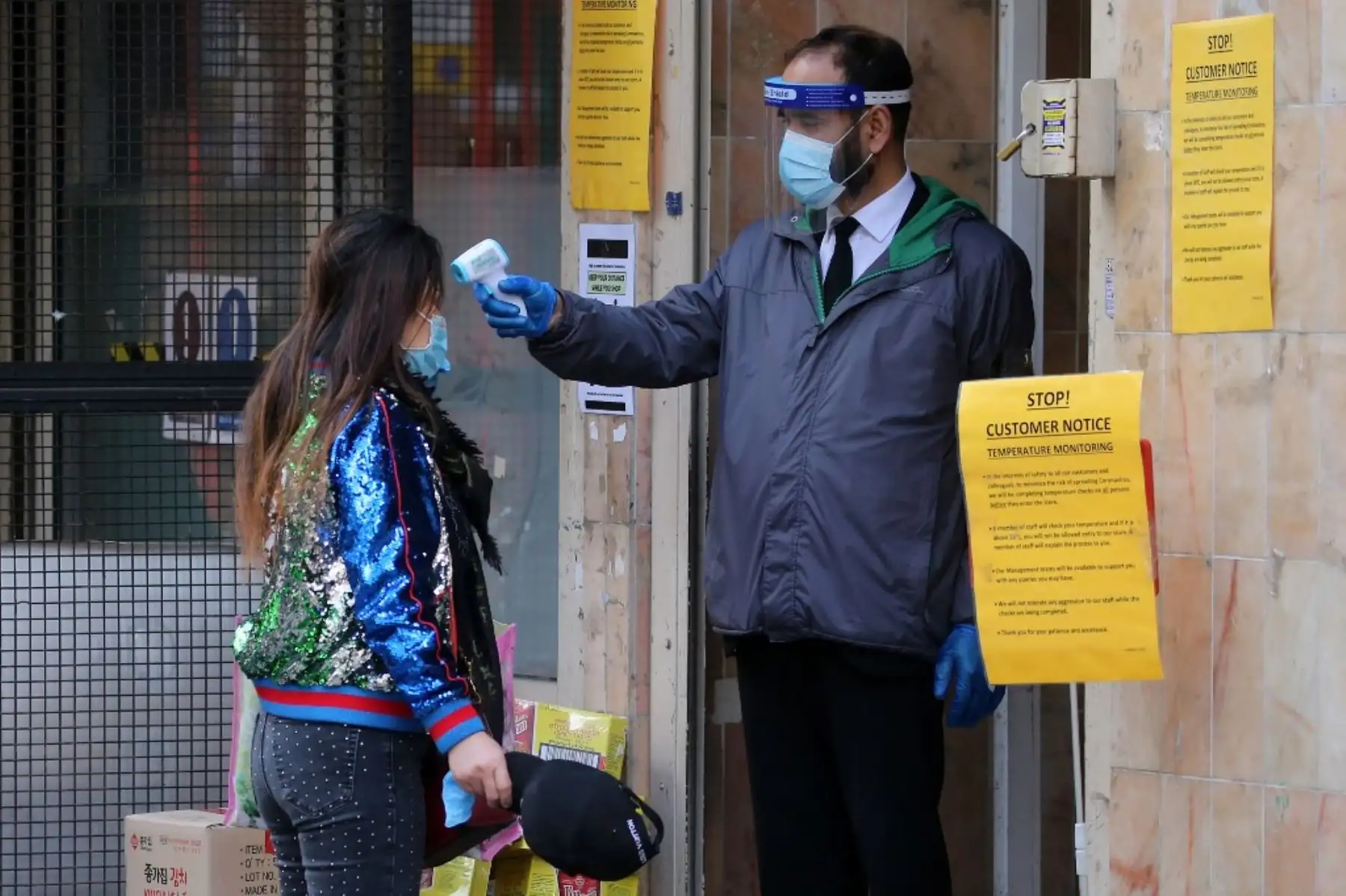 Un guardia de seguridad utiliza un escáner portátil para medir la temperatura de un cliente que desea ingresar a un supermercado asiático en el distrito de Chinatown en Londres. Foto: AFP