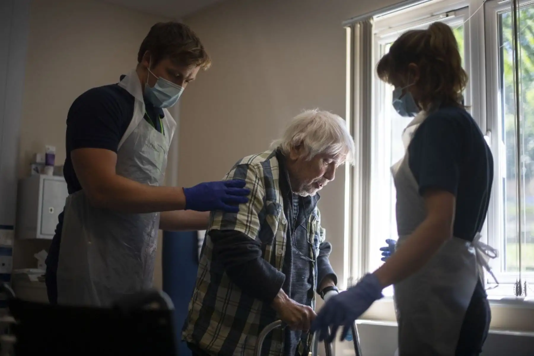 Los trabajadores de apoyo de rehabilitación realizan un tratamiento de fisioterapia en el paciente Michael Kidd, de 82 años. Foto: AFP