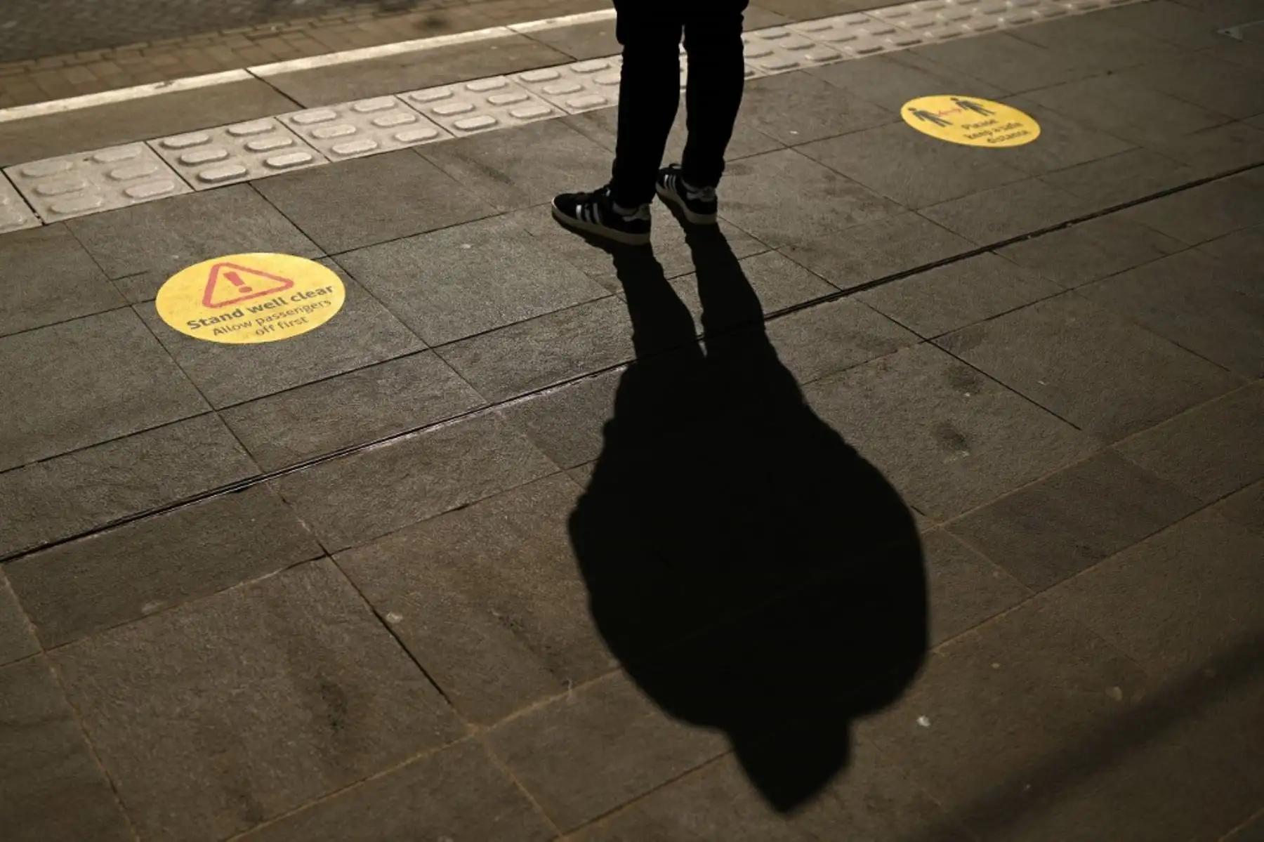 Un hombre espera entre los marcadores que aconsejan a los viajeros sobre el distanciamiento social en una plataforma de tranvía en el centro de Manchester. Foto: AFP