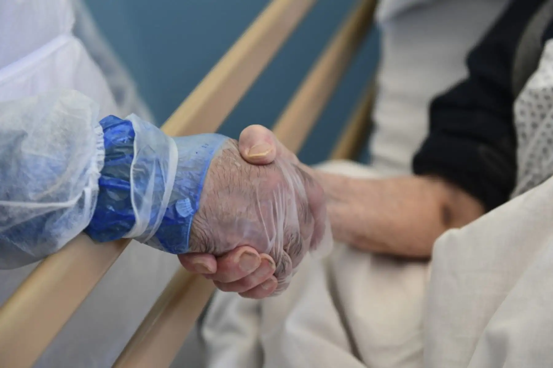 El médico cubano Leosvel Pérez Gutiérrez, uno de los trabajadores de la salud cubanos que brindó ayuda humanitaria en Sierra Leona para eliminar el brote de ébola, sostiene la mano de una anciana que se recupera de COVID-19. Foto: AFP