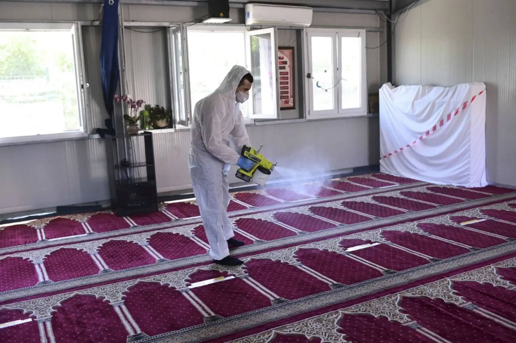 Un hombre desinfecta las alfombras después de la oración del viernes en medio de la pandemia de coronavirus COVID-19, en una mezquita en Milán. Foto: AFP