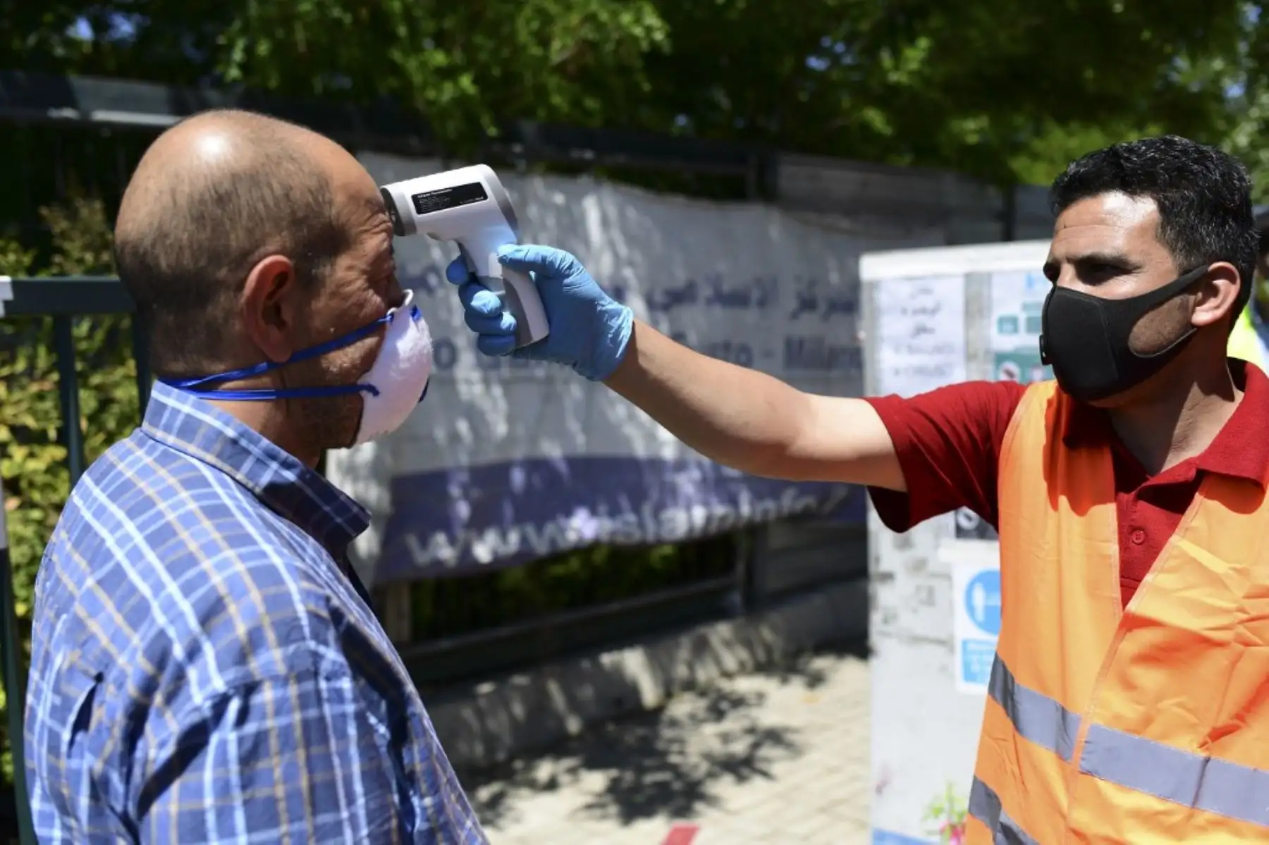 Un hombre con una máscara protectora mide la temperatura corporal de un fiel que llega para la oración del viernes en una mezquita en Milán. Foto: AFP