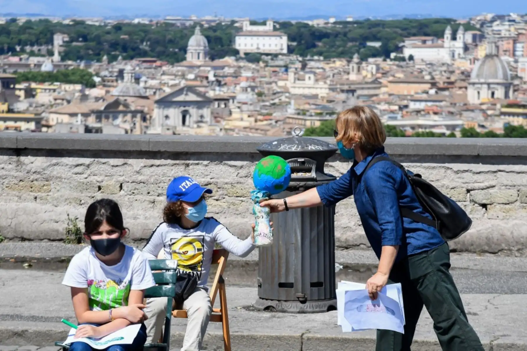 Un padre entrega un modelo de la Tierra a un niño mientras padres e hijos de la escuela pública primaria y secundaria de Roma "IC Largo Oriani" participan en un flashmob titulado "Open School". Foto: AFP