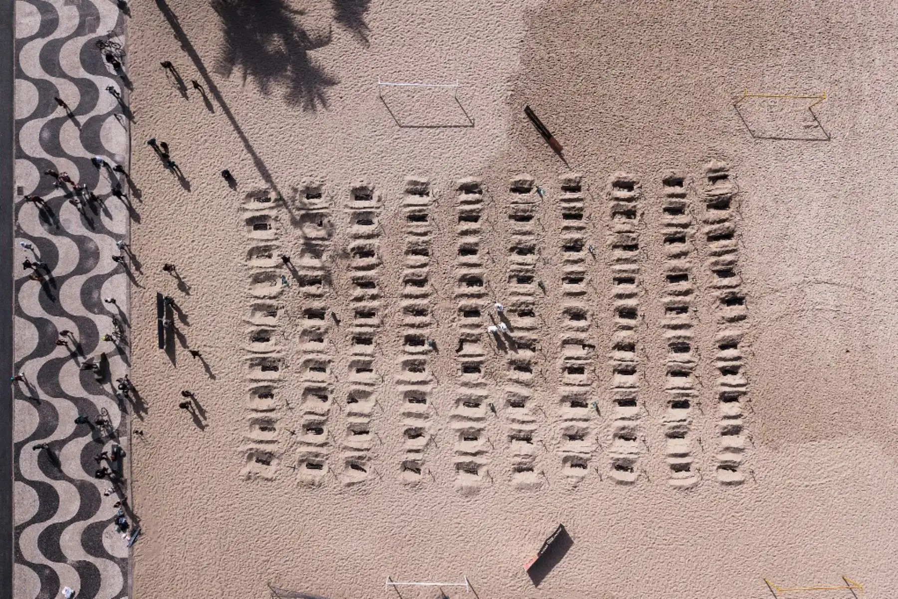 Vista aérea de activistas de la ONG brasileña Río de Paz cavando tumbas simuladas, en la playa de Copacabana, que simboliza las muertes por el coronavirus.
Foto: AFP