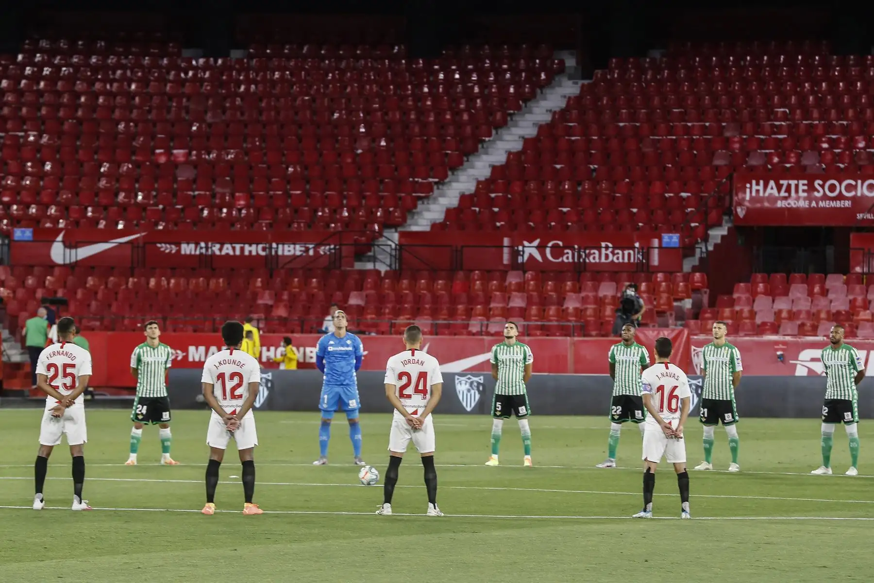 Jugadores del Betis y Sevilla guardan un minuto de silencio en memoria de las víctimas del covid 19 calientan momentos antes del partido de liga disputado en el estadio Sánchez Pizjuan y que es el primero de la Liga Santander después de tres meses sin fútbol por la pandemia de coronavirus.
Foto: EFE