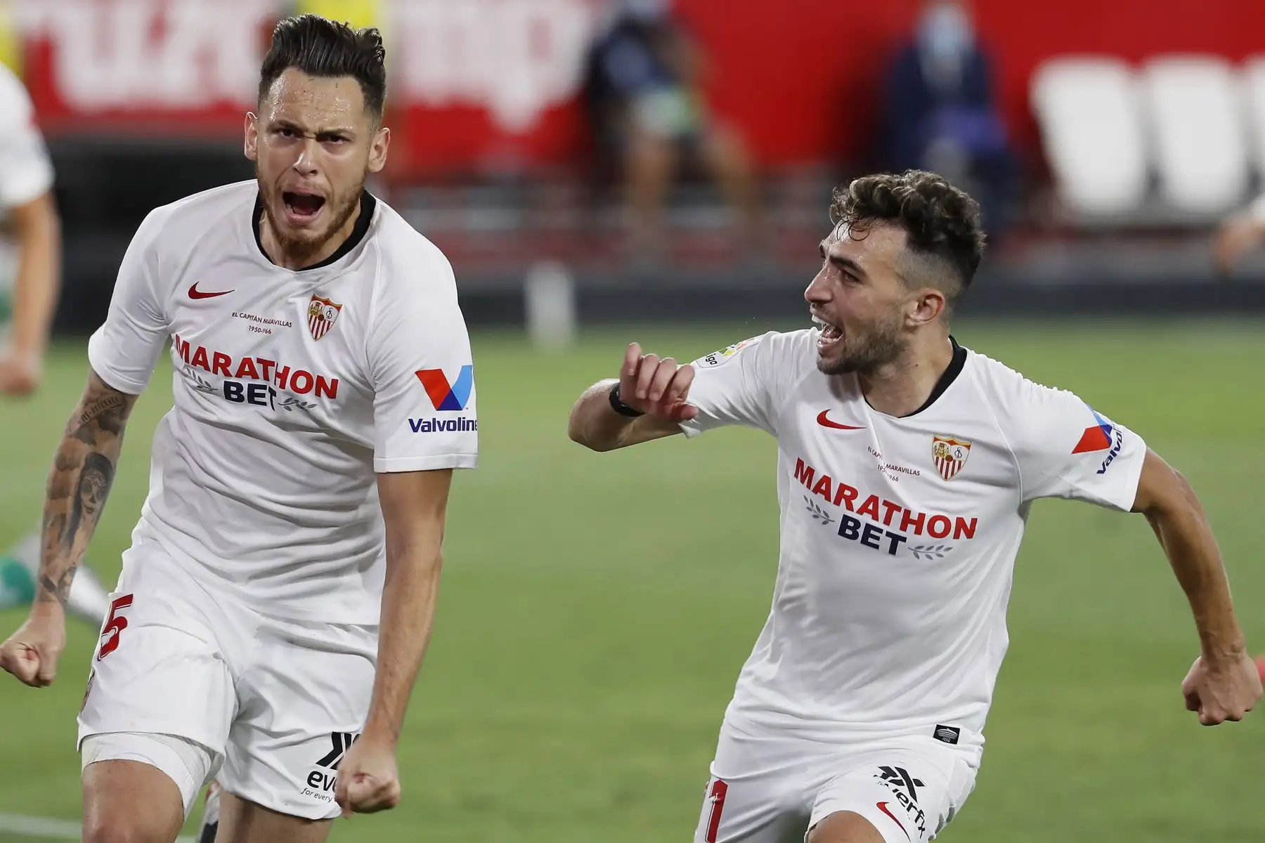 Los jugadores del Sevilla, el argentino Lucas Ocampos  y Munir, celebran el primer gol del equipo sevillista durante el encuentro correspondiente a la jornada 28 de primera división que disputan esta noche frente al Betis en el estadio Sánchez Pizjuán, primer encuentro tras el parón obligado de la liga provocado por la pandemia de coronavirus. 
Foto: EFE