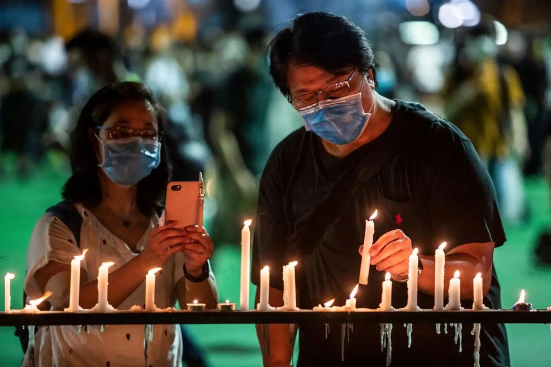 Un hombre coloca una vela en una barandilla durante una vigilia en el Victoria Park de Hong Kong. Foto: AFP