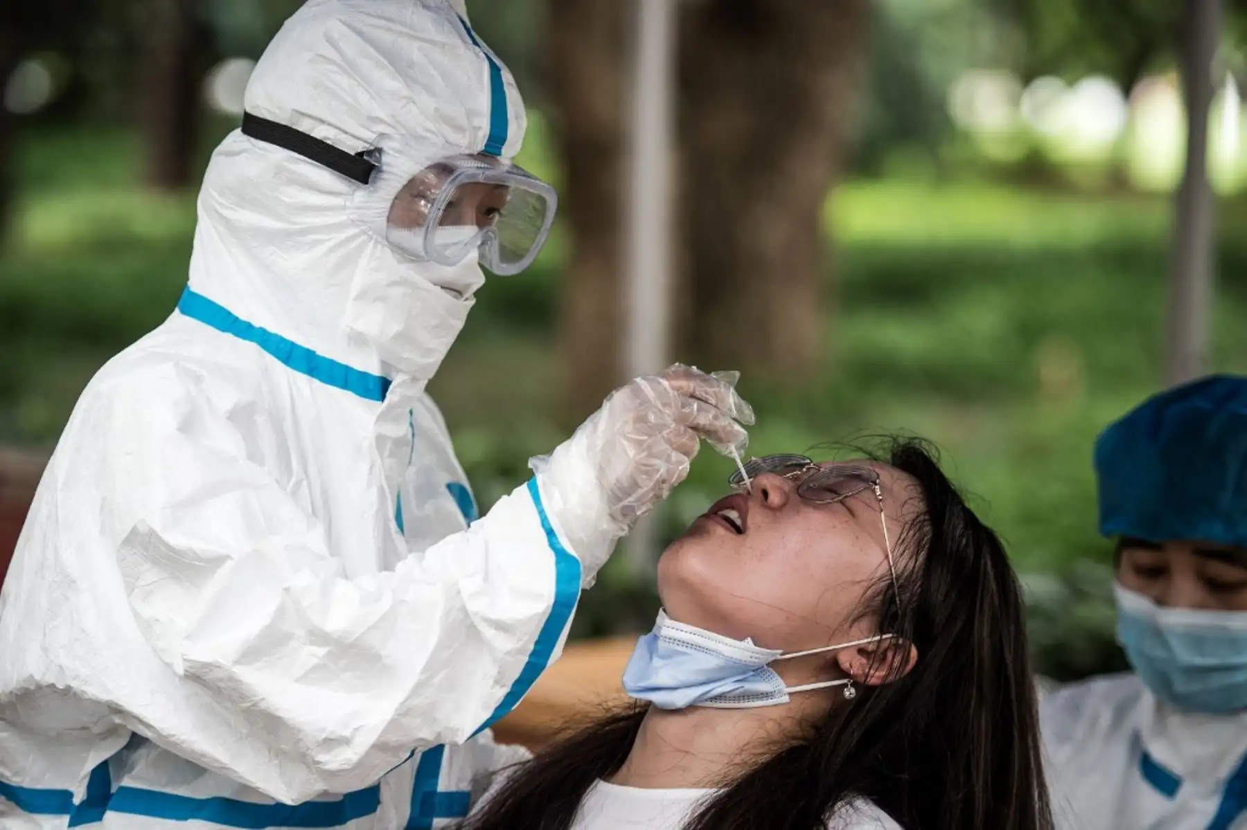 Una graduada universitaria está haciendo la prueba del coronavirus COVID-19 antes de ingresar al campus para recibir su certificado de graduación en la Universidad de Ciencia y Tecnología de Huazhong en Wuhan. Foto: AFP