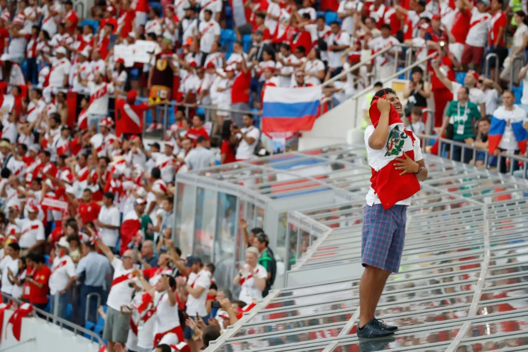 Un fanático de Perú celebra la victoria de su equipo sobre el techo de cristal de las cajas VIP después del partido de fútbol del Grupo C de la Copa Mundial de Rusia 2018 entre Australia y Perú en el Estadio Fisht en Sochi el 26 de junio de 2018. Foto: AFP