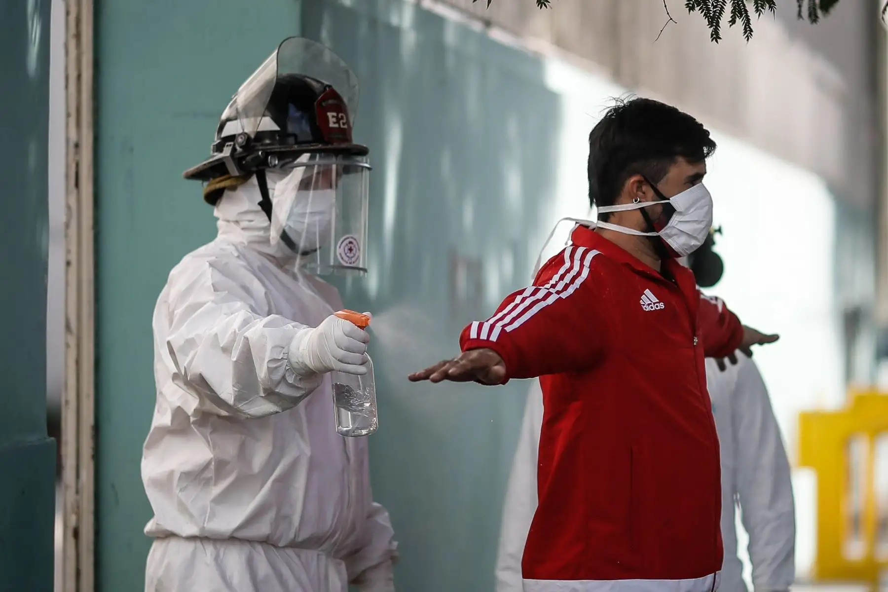 Un bombero rocía con alcohol a un hombre durante una jornada de tomas de pruebas de coronavirus este martes, en el barrio Constitución de Buenos Aires (Argentina). Foto: EFE
