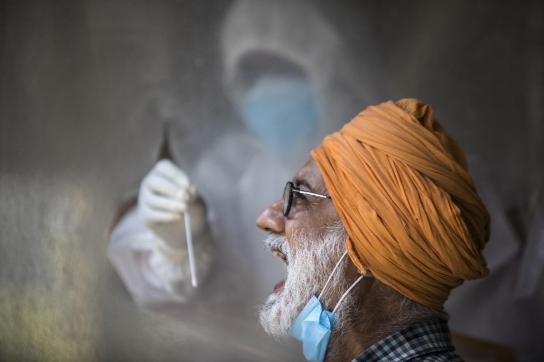 Un funcionario de salud recolecta una muestra de hisopo de un hombre para descartar la presencia del covid-19, en Nueva Delhi. Foto: AFP