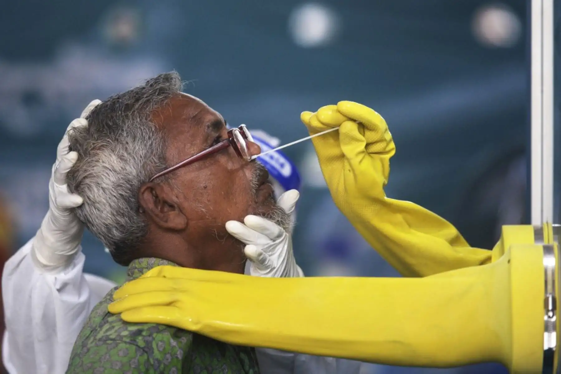 Un empleado de Mugda Medical College and Hospital recolecta una muestra de hisopo de un residente para analizar el coronavirus COVID-19, en Dhaka. Foto: AFP
