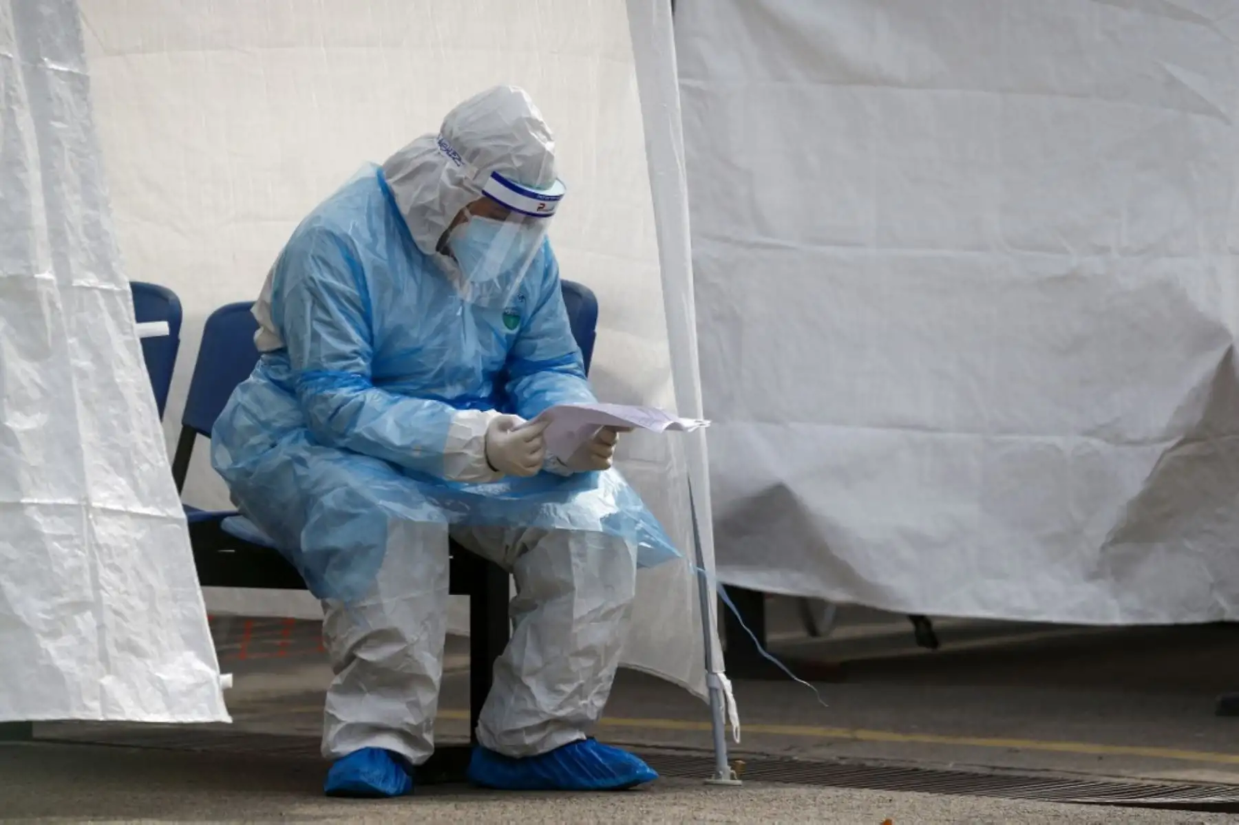 Un trabajador de la salud lee un documento mientras descansa en una de las carpas ubicadas fuera del hospital de San José de Santiago de Chile. Foto: AFP