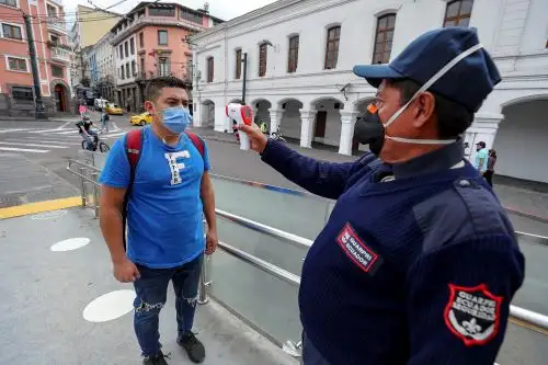 Un agente controla la temperatura de un ciudadano antes de permitir su ingreso a un local público en Ecuador. Foto: EFE