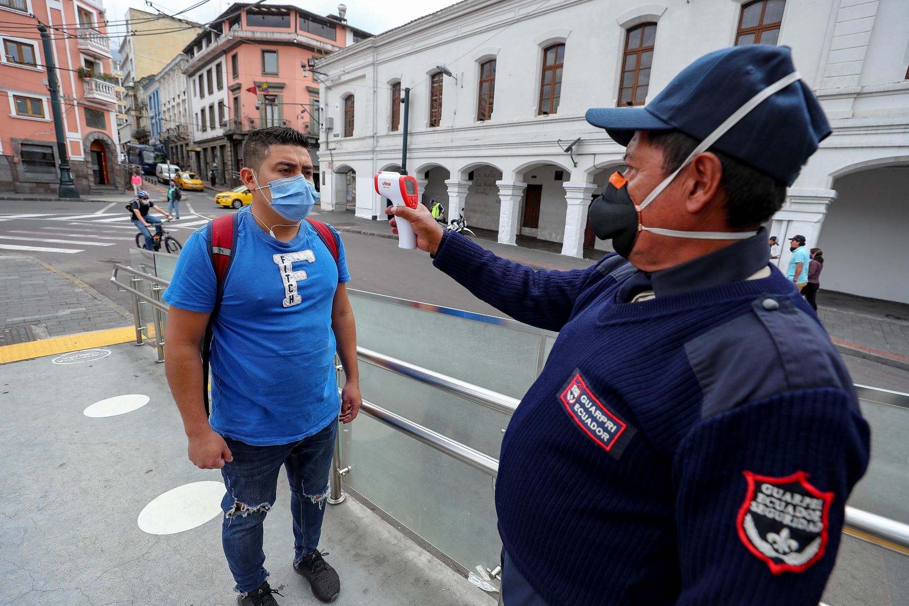 Un agente controla la temperatura de un ciudadano antes de permitir su ingreso a un local público en Ecuador. Foto: EFE