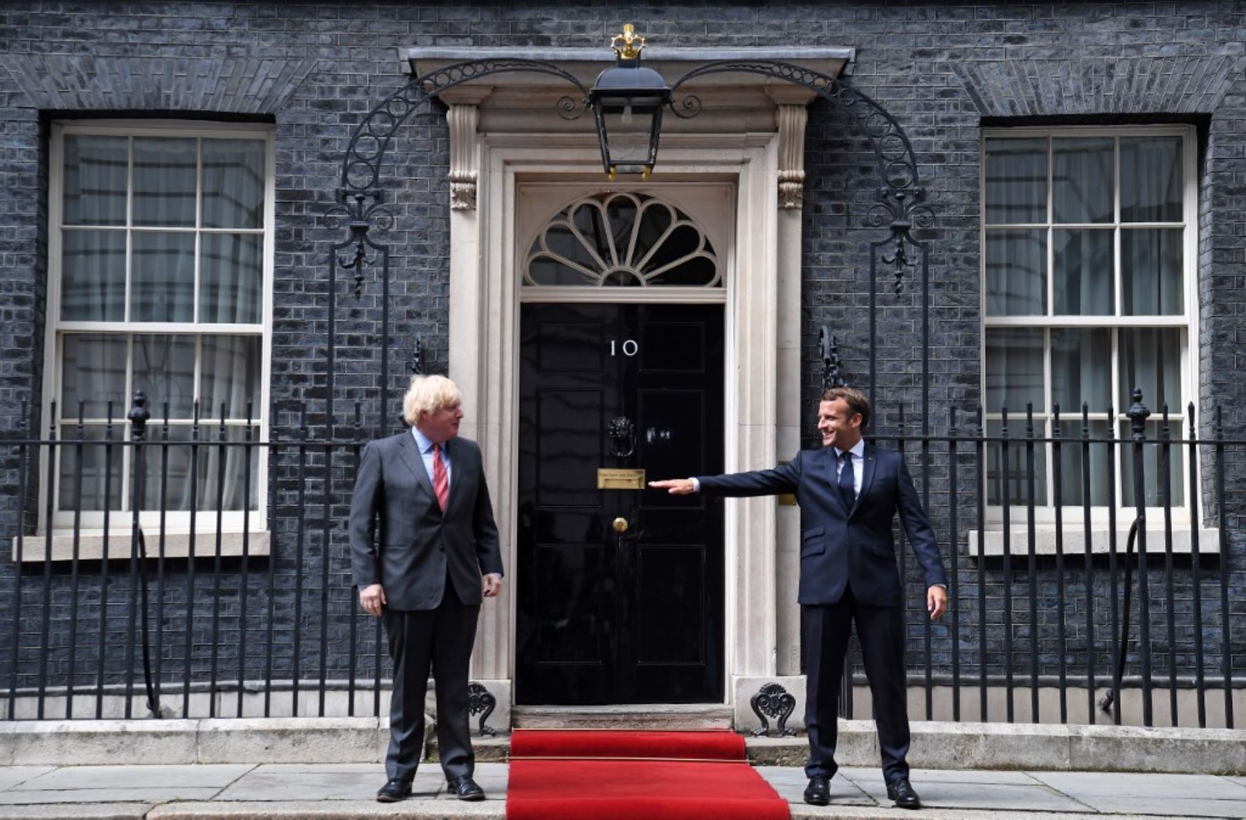 El presidente francés Emmanuel Macron hace gestos sobre permanecer socialmente distante junto al primer ministro británico Boris Johnson en el centro de Londres durante una actividad. Foto: AFP