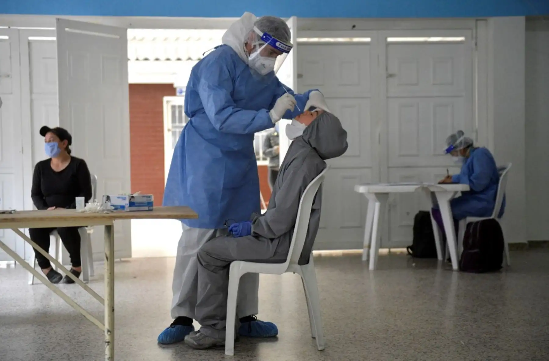 Un trabajador de salud toma una muestra para una prueba COVID-19 de un residente del vecindario Kennedy, una de las áreas con la tasa más alta de casos positivos en Bogotá. Foto: AFP