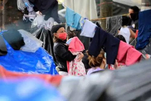 Una mujer carga a su bebé en un campamento improvisado donde los inmigrantes venezolanos desempleados y sin hogar permanecen durante la pandemia del covid-19 en Bogotá. Foto: AFP