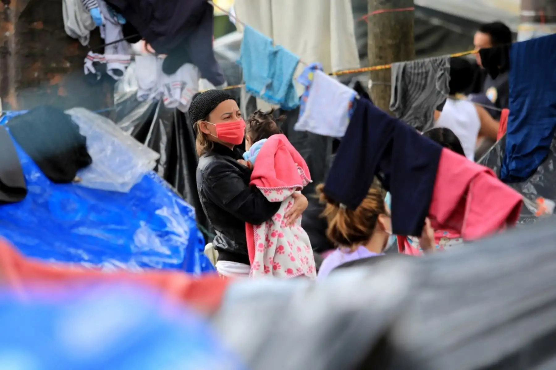 Una mujer carga a su bebé en un campamento improvisado donde los inmigrantes venezolanos desempleados y sin hogar permanecen durante la pandemia del covid-19 en Bogotá. Foto: AFP