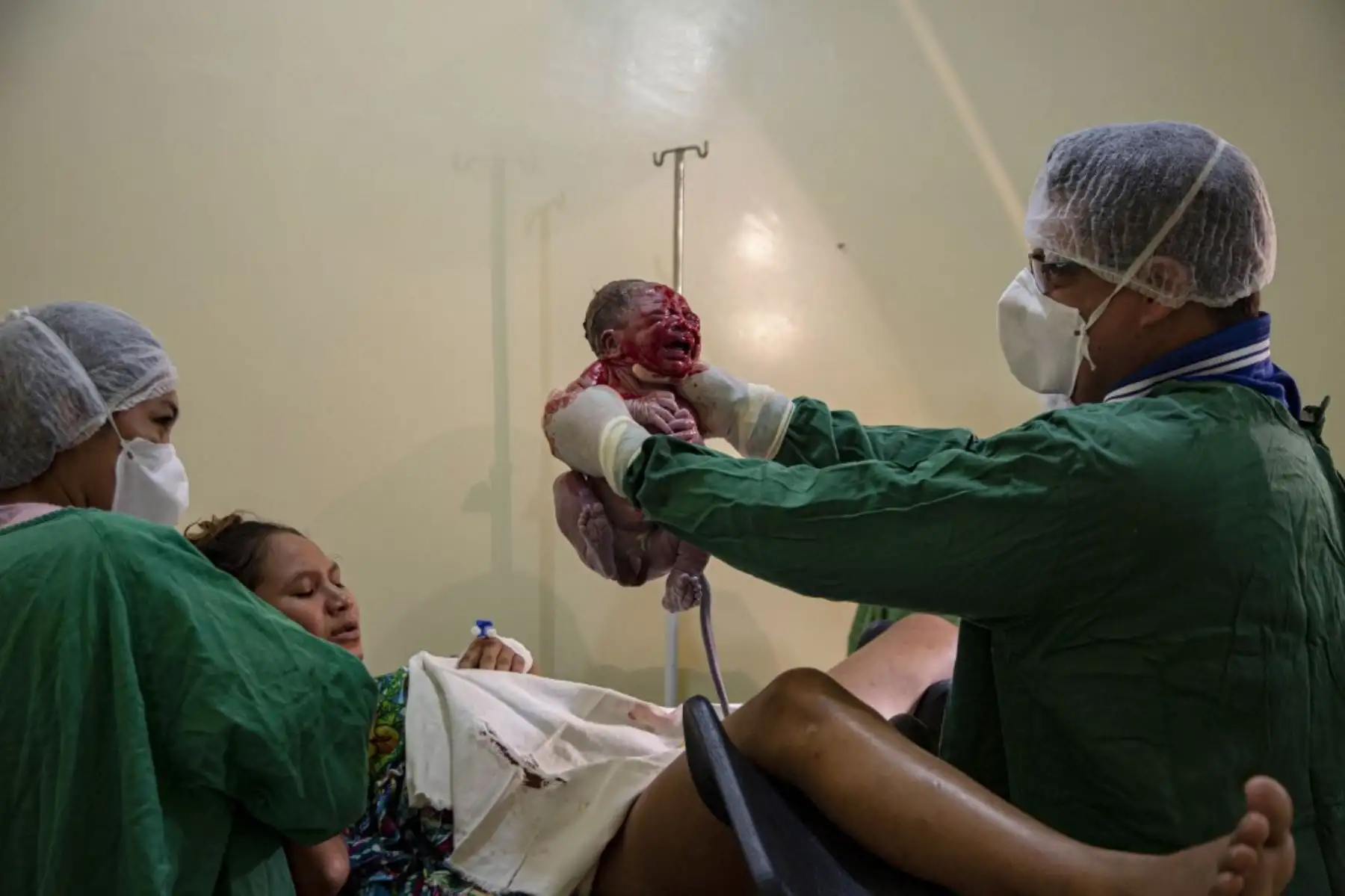 Un médico sostiene a un niño recién nacido mientras su madre, una paciente con síntomas de covid-19, observa inmediatamente después de dar a luz en el Hospital Municipal de Melgaco en la ciudad de Melgaco. Foto: AFP